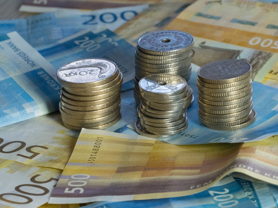 Litt norsk valuta på et bord. Noen 500-lapper og stabler med mynter. Illustrasjonsfoto.